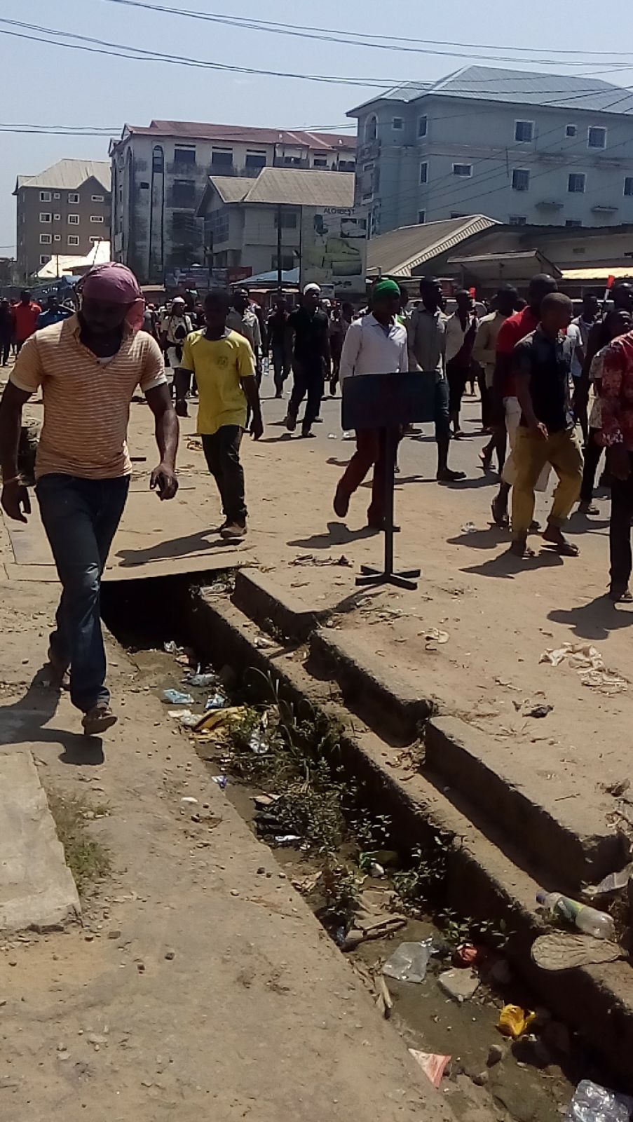 Un groupe de jeunes manifestants se rassemble dans les rues du Nigeria pour protester contre la corruption et la discrimination liée à l'âge. Ils tiennent des pancartes et des banderoles demandant justice et changement. L'atmosphère est empreinte d'énergie et d'espoir.