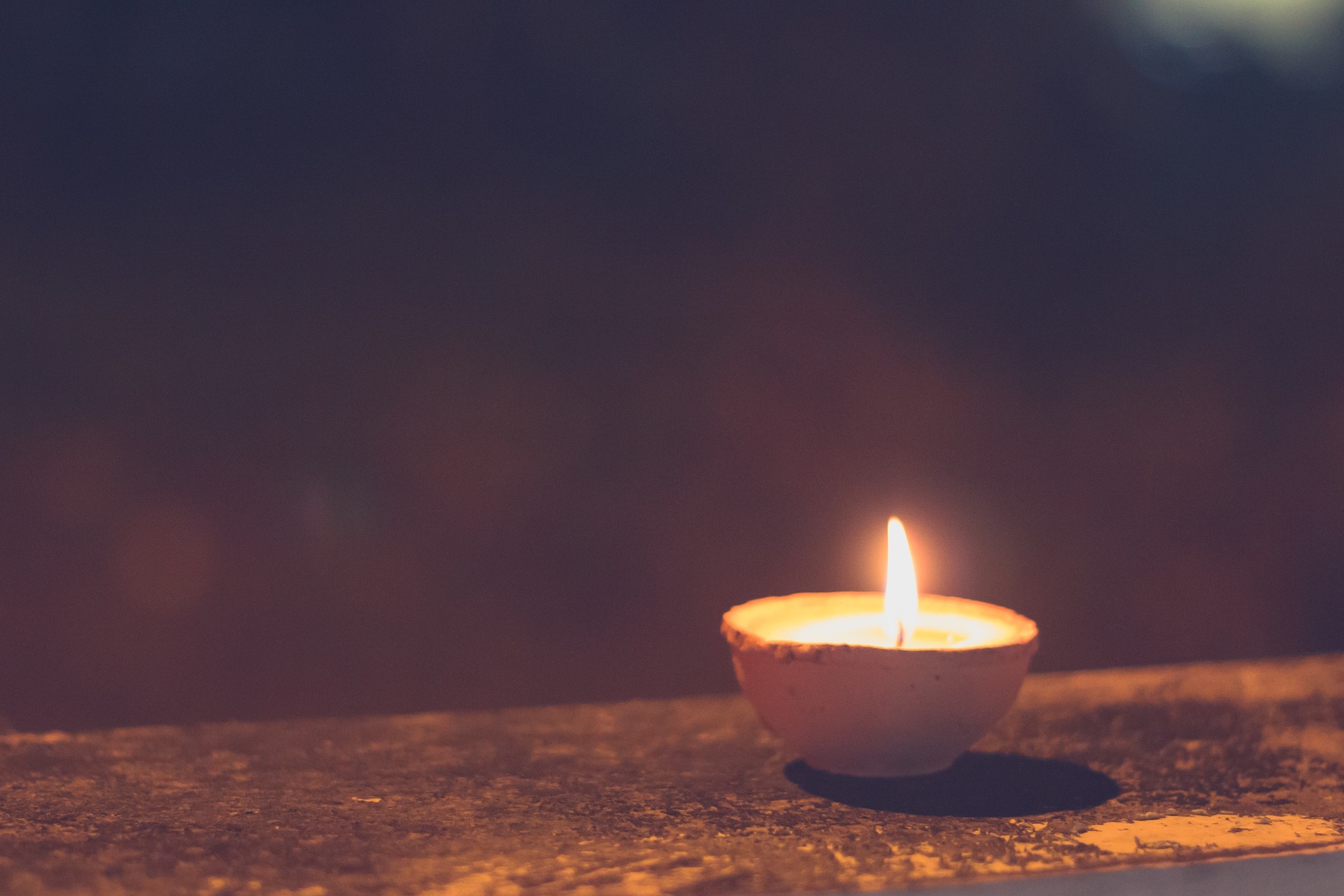 Symbolbild: Eine brennende Kerze als Zeichen der Hoffnung und Zuversicht in dunklen Zeiten